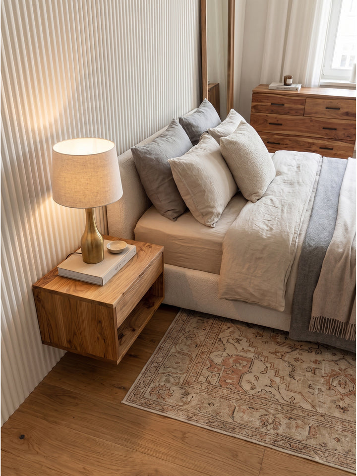 Blick von oben auf den Wandnachttisch aus Holz neben einem Polsterbett mit Leinenbezug im eleganten Schlafzimmer_