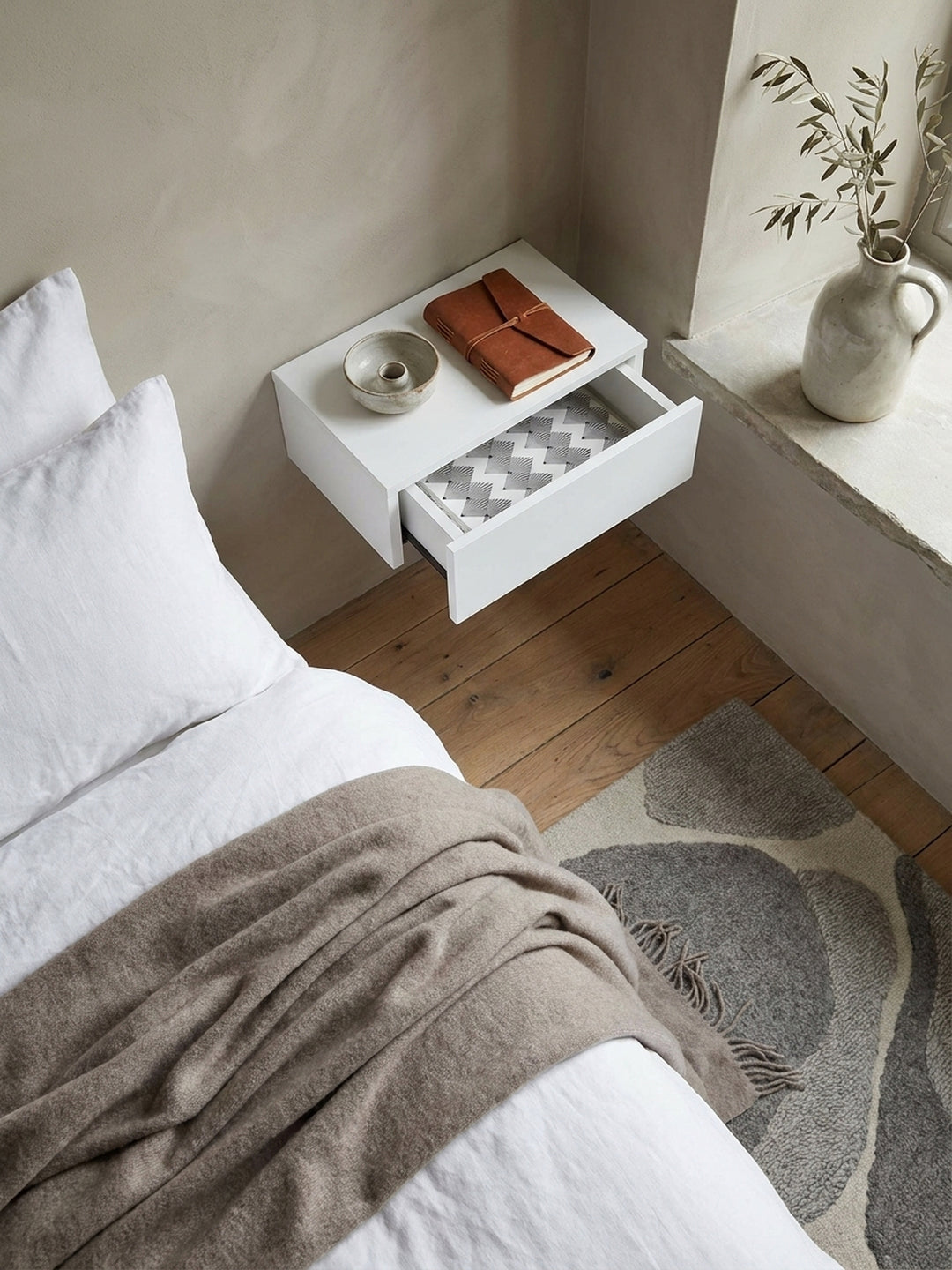 Ansicht von oben auf die minimalistische Wandkonsole mit Schublade, montiert über einem echten Eichenparkettboden im hellen Schlafzimmer_