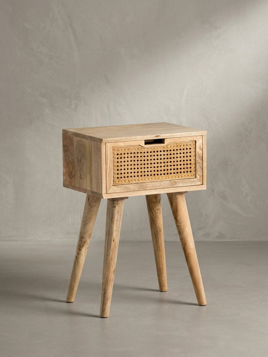 Freigestellte Frontalansicht der Nachtkonsole aus massivem Mangoholz, die schlanke Silhouette mit ausgestellten Beinen und die Schublade mit Wiener Geflecht zeigend._