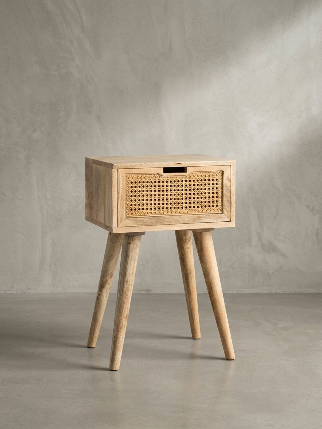 Dreiviertelansicht des Nachttisches mit Rattan, die die ausdrucksstarke Maserung des Mangoholzes an der Seite und die hochwertige Verarbeitung der Schublade hervorhebt._