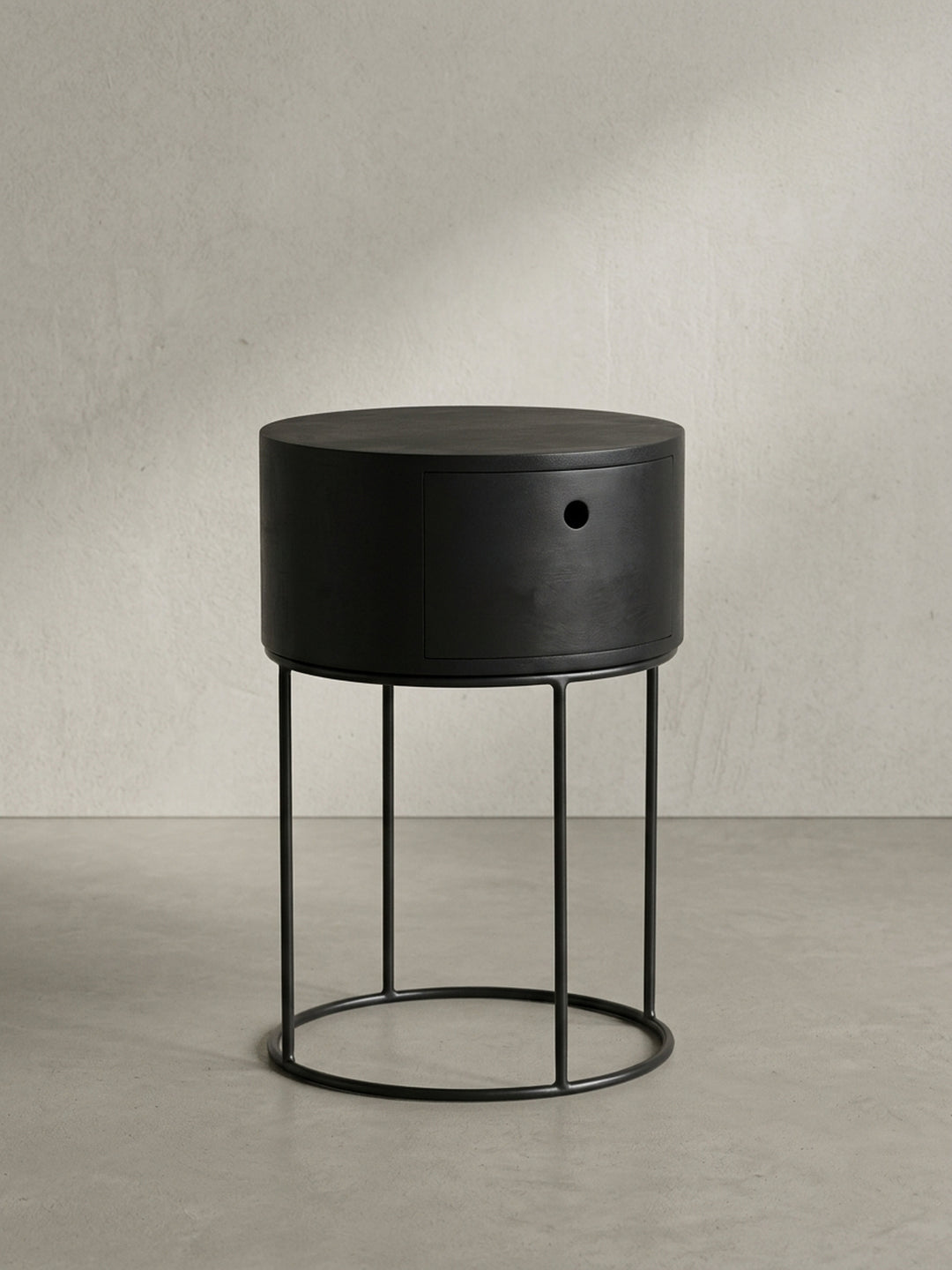Nahaufnahme des runden Eingriffs der Schublade des schwarzen Nachttisches, ein Beispiel für minimalistisches und funktionales Design ohne Griffe._