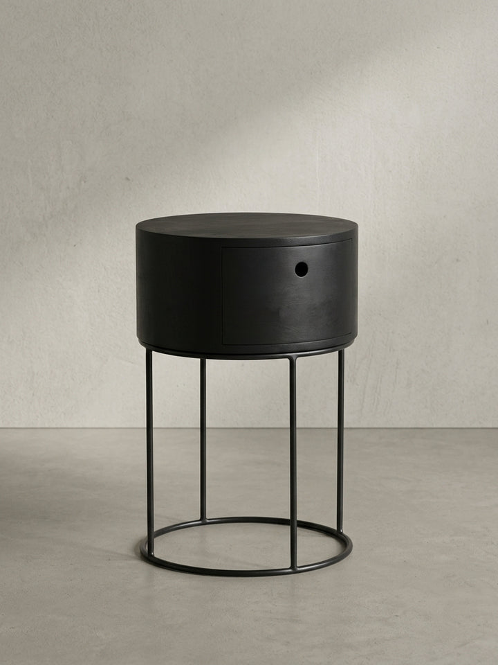Nahaufnahme des runden Eingriffs der Schublade des schwarzen Nachttisches, ein Beispiel für minimalistisches und funktionales Design ohne Griffe._