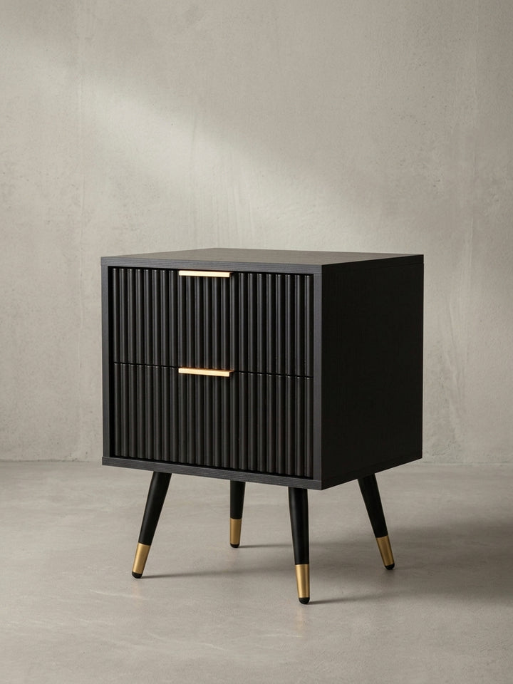 Seitenansicht des schmalen Nachttisches, die seine schlanke Silhouette und die eleganten, konischen Beine mit Goldkappen hervorhebt._