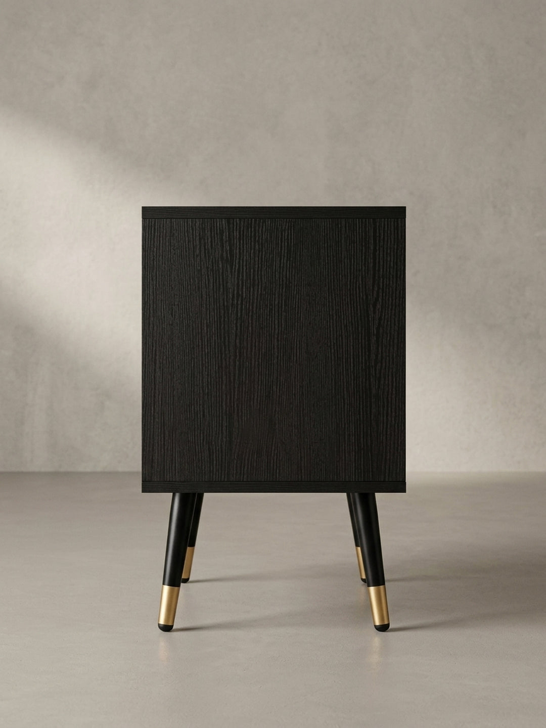 Nahaufnahme des minimalistischen, goldfarbenen Griffs an der geriffelten Schubladenfront des schwarzen Design-Nachttisches._