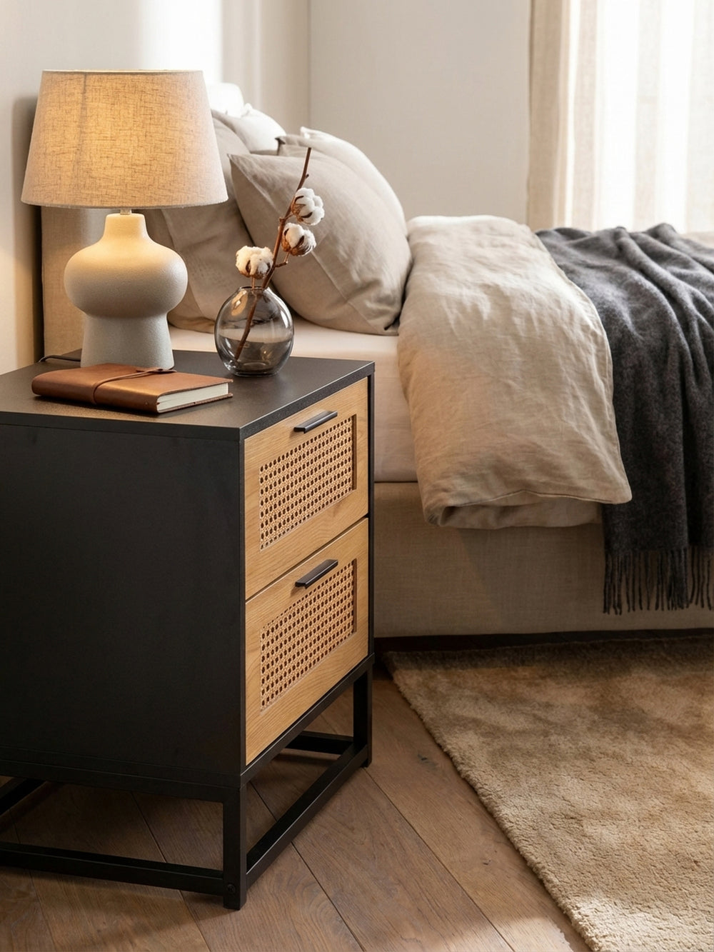 Ein gemütliches Abend-Vignette: Auf dem schwarzen Nachttisch steht eine Keramiklampe, ein Glas Wasser und ein Buch, bereit für eine ruhige Nacht._