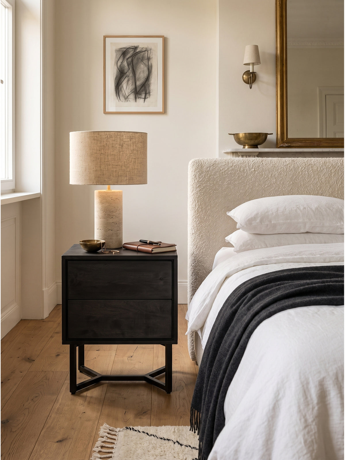 Elegantes Schlafzimmer-Set mit einem Nachttisch aus schwarzem Akazienholz und einem hellen Polsterbett harmonisch kombiniert.