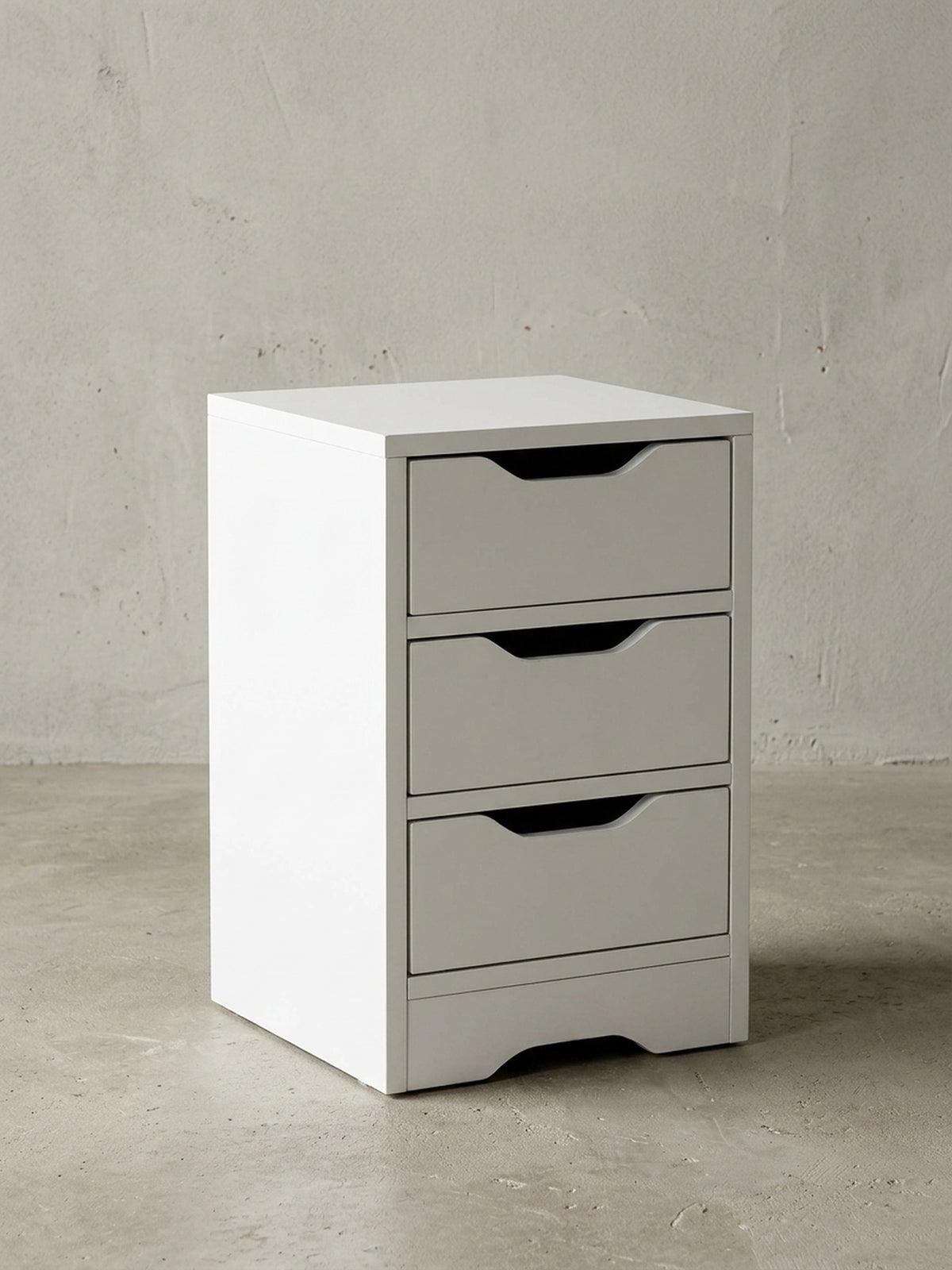 Frontale Ansicht der weißen Nachtkonsole mit drei geräumigen Schubladen. Die praktischen Griffmulden unterstreichen das minimalistische, grifflose Design des Möbelstücks._