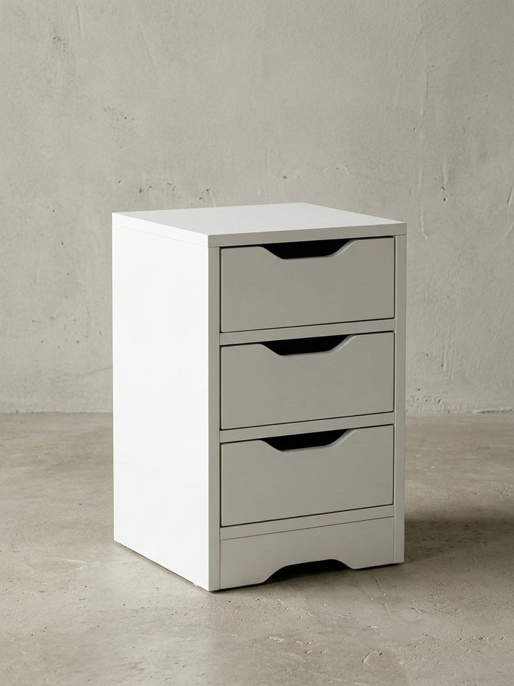 Frontale Ansicht der weißen Nachtkonsole mit drei geräumigen Schubladen. Die praktischen Griffmulden unterstreichen das minimalistische, grifflose Design des Möbelstücks._