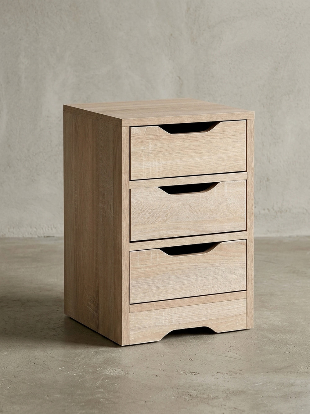 Schlichter Nachttisch aus Holzwerkstoff in Frontalansicht vor weißem Hintergrund. Die drei übereinanderliegenden Schubladen bieten viel Stauraum bei kompakten Maßen von 31x49 cm._