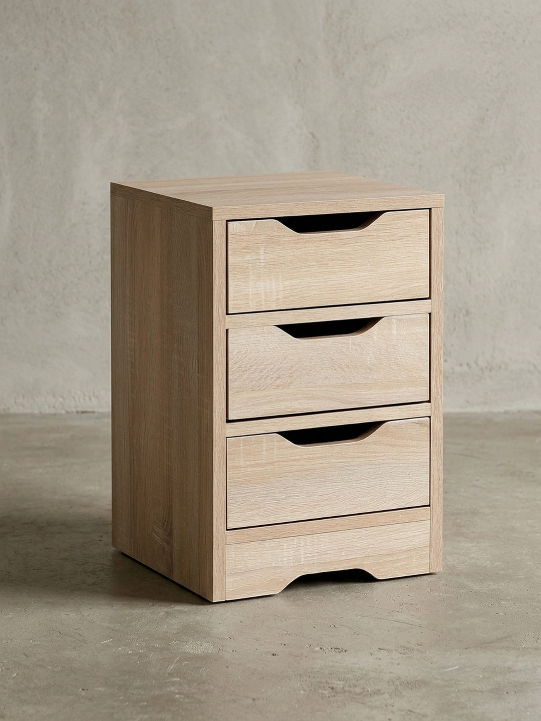 Schlichter Nachttisch aus Holzwerkstoff in Frontalansicht vor weißem Hintergrund. Die drei übereinanderliegenden Schubladen bieten viel Stauraum bei kompakten Maßen von 31x49 cm._