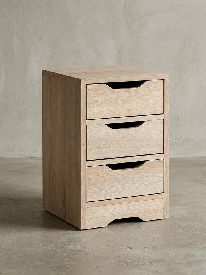 Schlichter Nachttisch aus Holzwerkstoff in Frontalansicht vor weißem Hintergrund. Die drei übereinanderliegenden Schubladen bieten viel Stauraum bei kompakten Maßen von 31x49 cm._