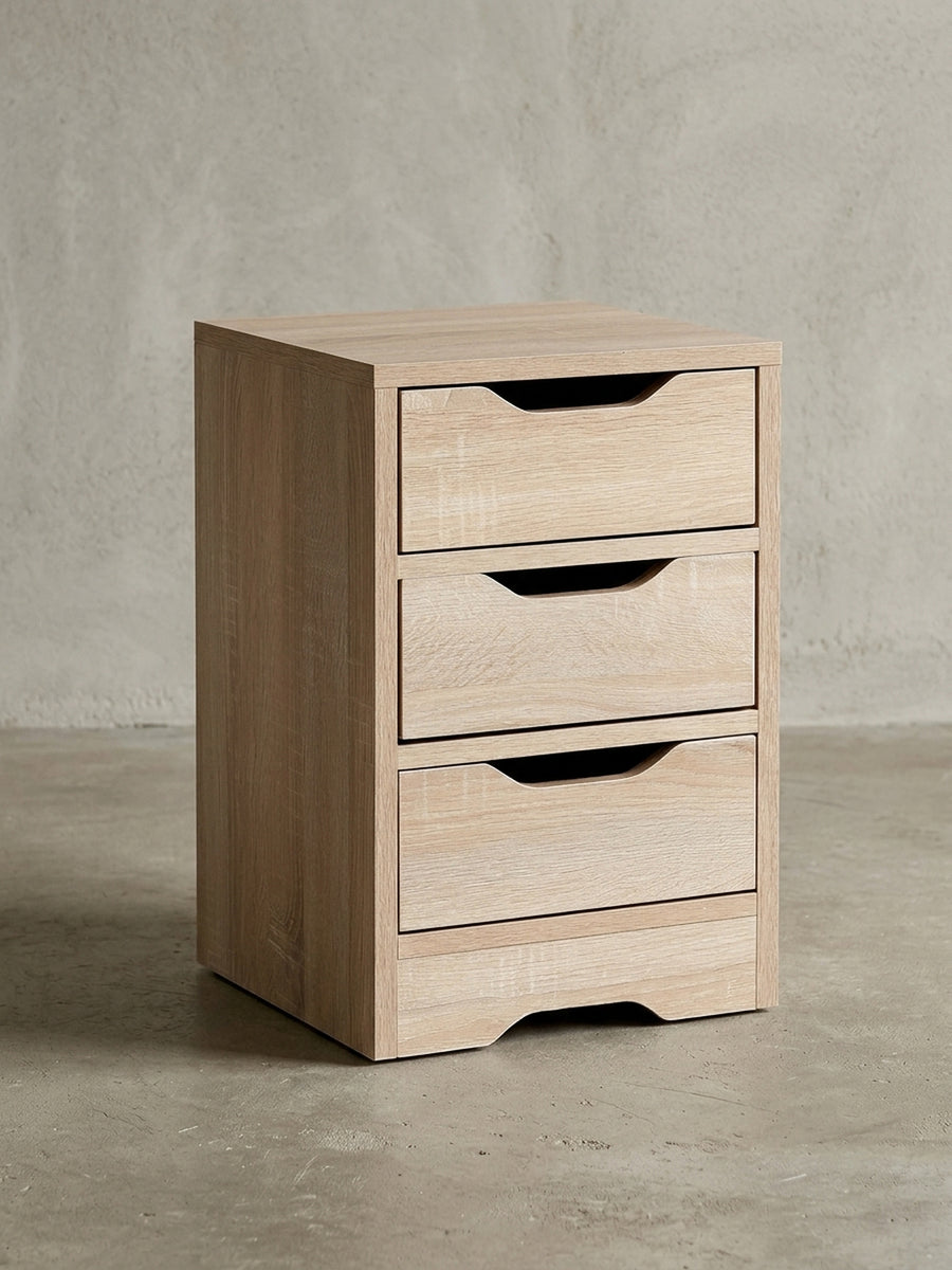 Schlichter Nachttisch aus Holzwerkstoff in Frontalansicht vor weißem Hintergrund. Die drei übereinanderliegenden Schubladen bieten viel Stauraum bei kompakten Maßen von 31x49 cm._