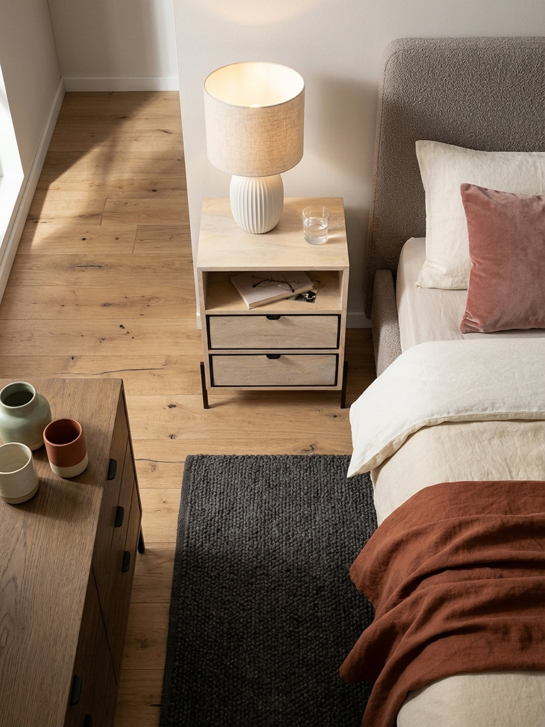 Design-Nachtkonsole mit schwarzem Metallgestell von oben betrachtet, perfekt arrangiert auf einem dunklen Bouclé-Teppich im Schlafzimmer._