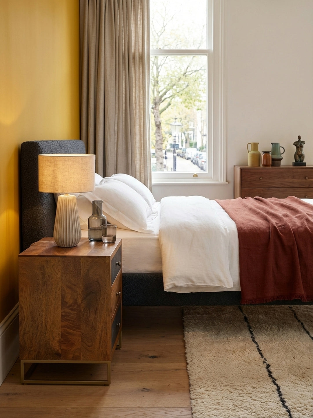 Der hohe Nachttisch in Braun und Steinoptik harmoniert perfekt mit dem weißen Leinenbettzeug und einem weichen Teppich und schafft ein stimmiges Schlafzimmer-Ambiente._