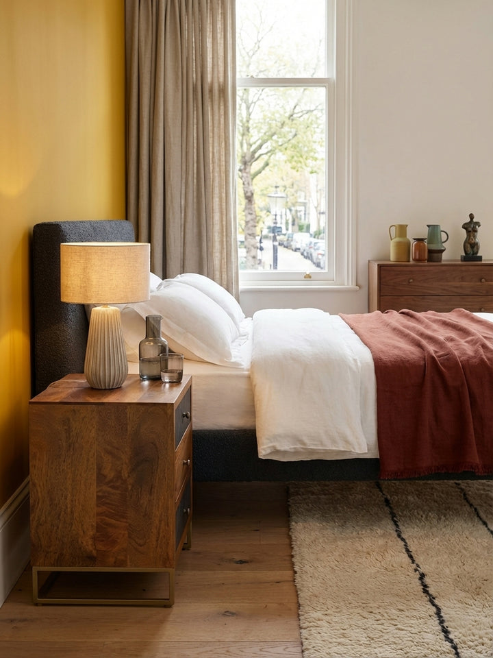 Der hohe Nachttisch in Braun und Steinoptik harmoniert perfekt mit dem weißen Leinenbettzeug und einem weichen Teppich und schafft ein stimmiges Schlafzimmer-Ambiente._