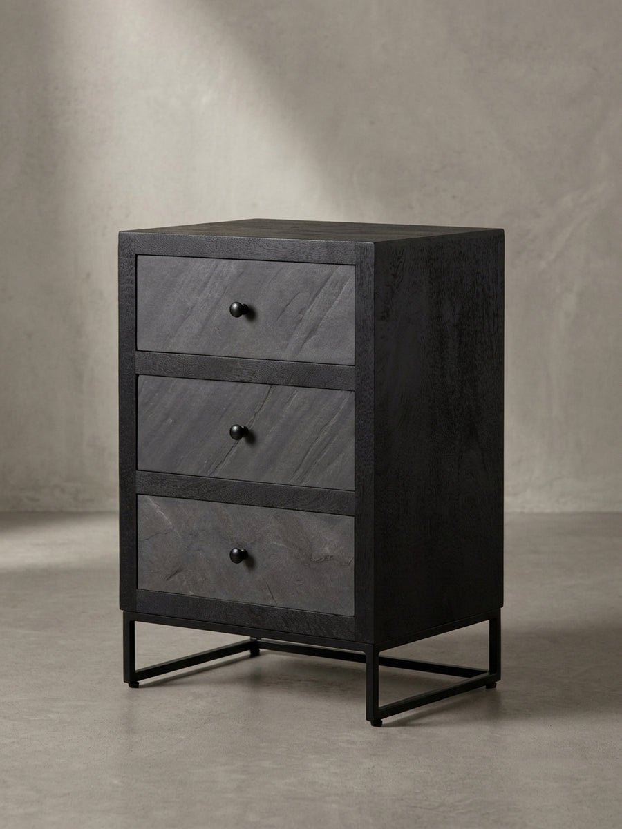 Ein Detail-Shot des pulverbeschichteten Metallgriffs am schwarzen Nachttisch, der den minimalistischen und industriellen Charakter unterstreicht._