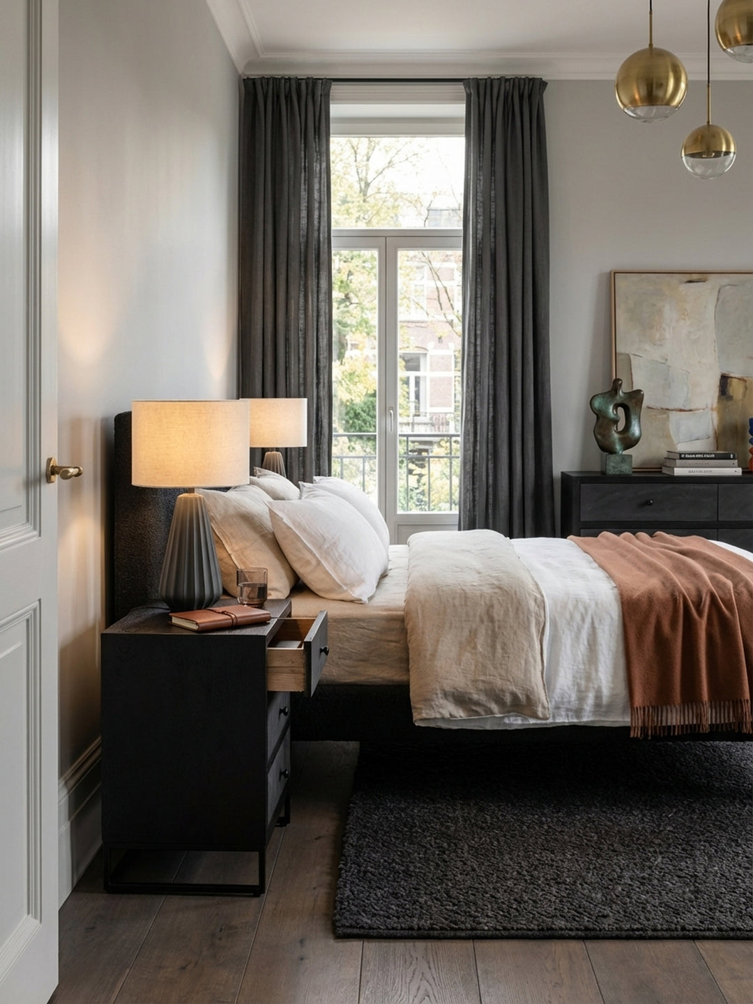 Stilvoller Nachttisch aus schwarzem Mangoholz und Steinoptik in einem minimalistischen Schlafzimmer mit Holzboden und Leinenbettwäsche._