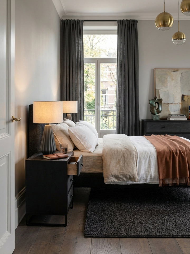 Stilvoller Nachttisch aus schwarzem Mangoholz und Steinoptik in einem minimalistischen Schlafzimmer mit Holzboden und Leinenbettwäsche._