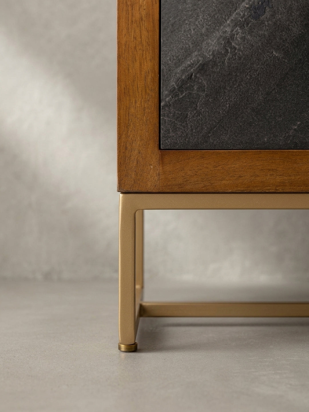 Nahaufnahme eines Messinggriffs an der grauen Schublade in Steinoptik, ein Detail des hochwertigen Nachttisches aus braunem Mango-Massivholz für das Schlafzimmer._