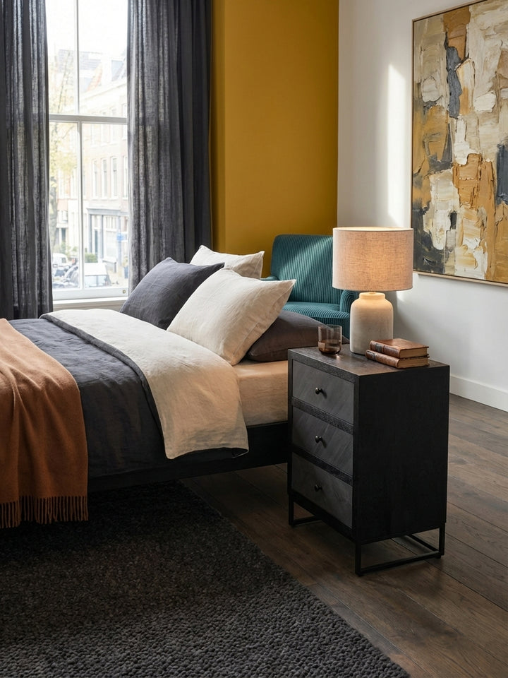 Der schmale Nachttisch aus massivem Mangoholz harmoniert perfekt mit einem niedrigen Sideboard und einem dunklen Holzbett in einem modernen Ambiente._