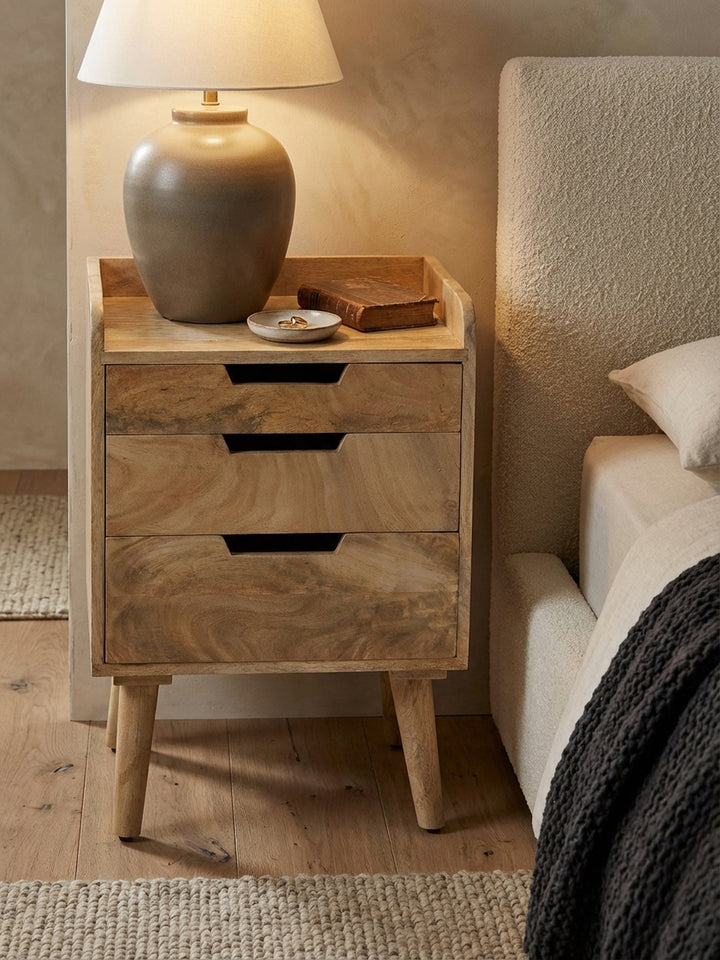 Design-Nachttisch mit einer kleinen Keramiklampe und einem aufgeschlagenen Buch, schafft eine gemütliche Leseatmosphäre am Abend._
