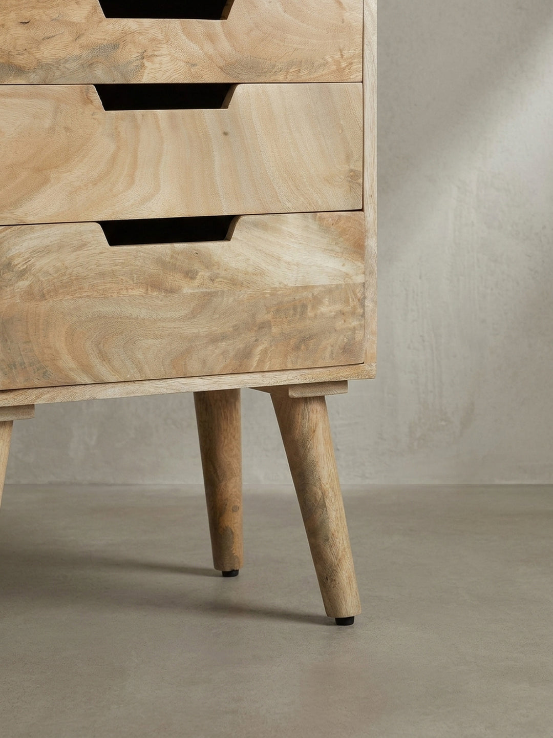 Detailaufnahme eines grifflosen Ausschnitts an einer Schublade des Nachttisches, die die handwerkliche Qualität des Mangoholzes betont._
