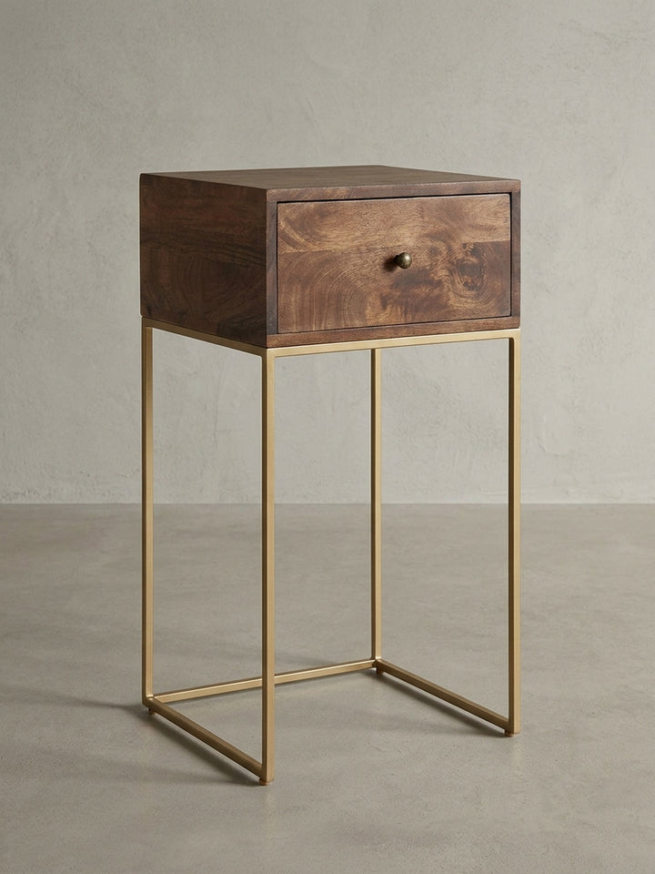 Frontansicht des Nachttisches aus Mango Massivholz auf weißem Hintergrund. Das schlanke, 75,5 cm hohe Design mit goldfarbenem Metallgestell wird deutlich sichtbar._