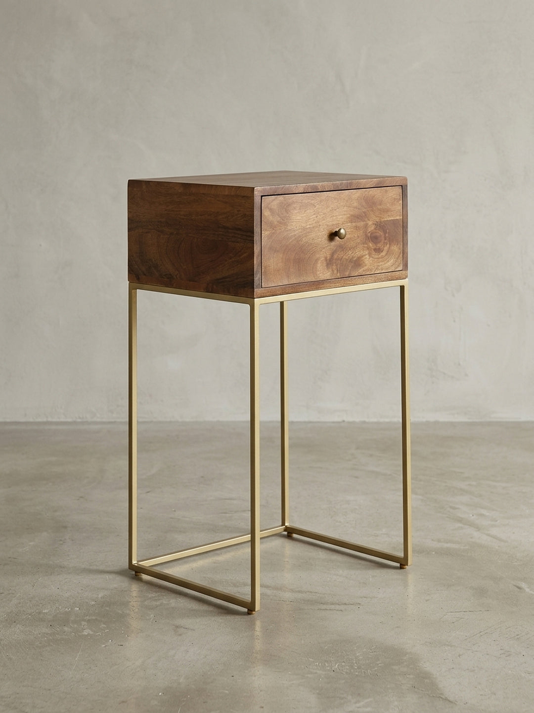 Dreiviertelansicht des Design Nachttisches, die das Zusammenspiel von massivem Holzkorpus und filigranem Eisengestell in Goldoptik zeigt. Ideal für hohe Boxspringbetten._