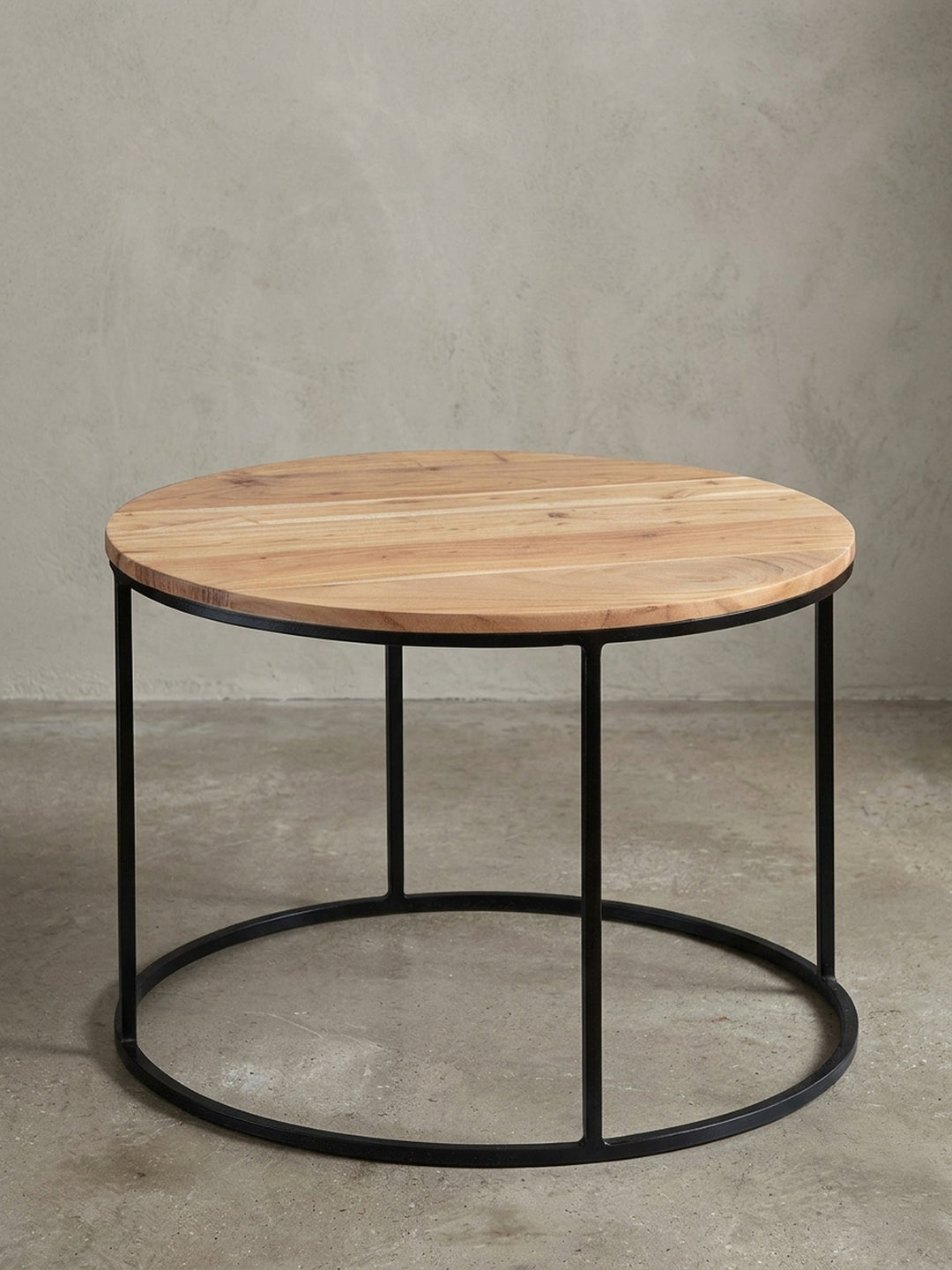 Freigestellter Couchtisch Akazie Massivholz mit schwarzem Metallgestell. Der 60 cm breite runde Sofatisch zeigt sein minimalistisches Industrie-Design auf weißem Hintergrund._