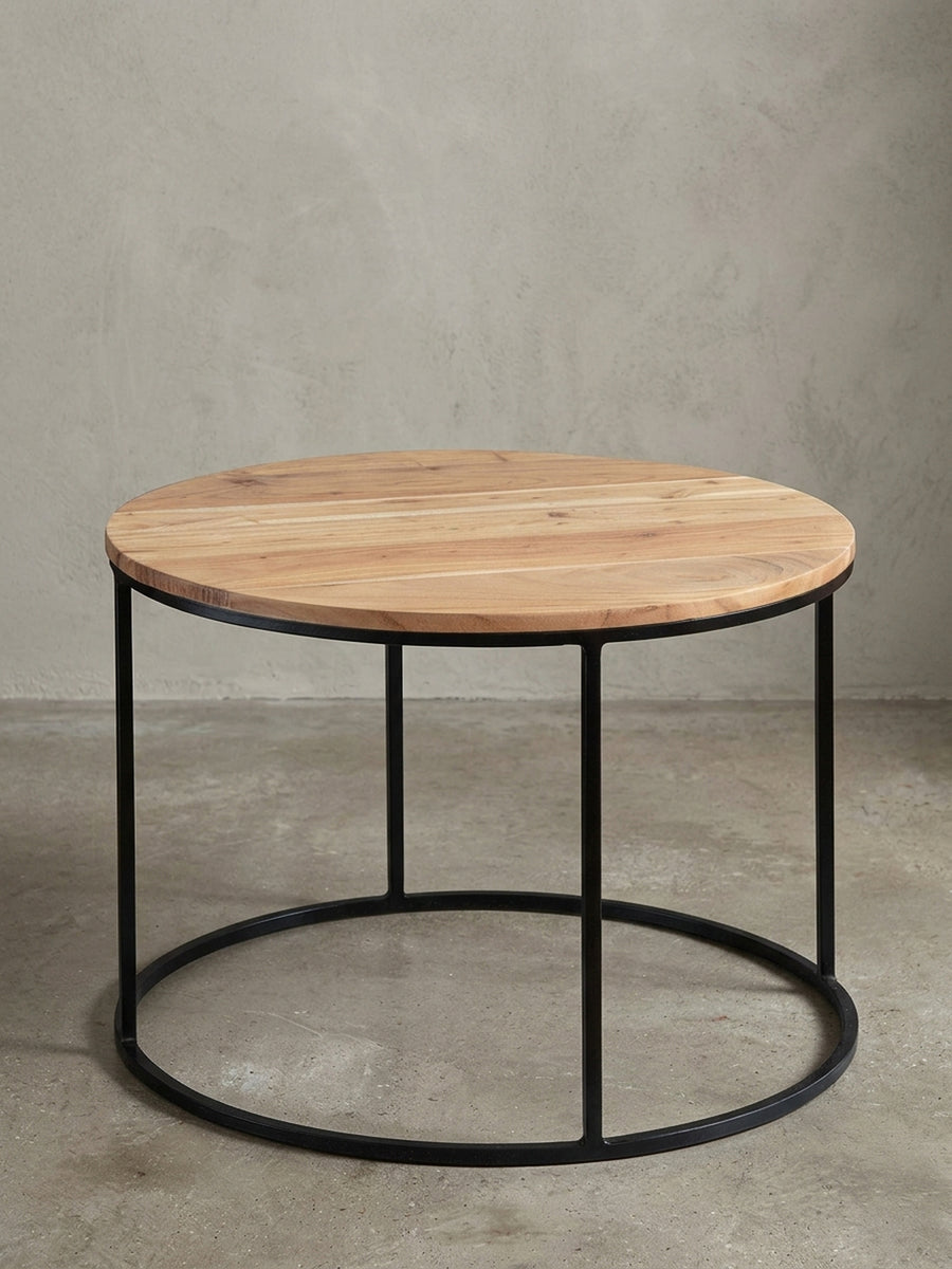 Freigestellter Couchtisch Akazie Massivholz mit schwarzem Metallgestell. Der 60 cm breite runde Sofatisch zeigt sein minimalistisches Industrie-Design auf weißem Hintergrund._