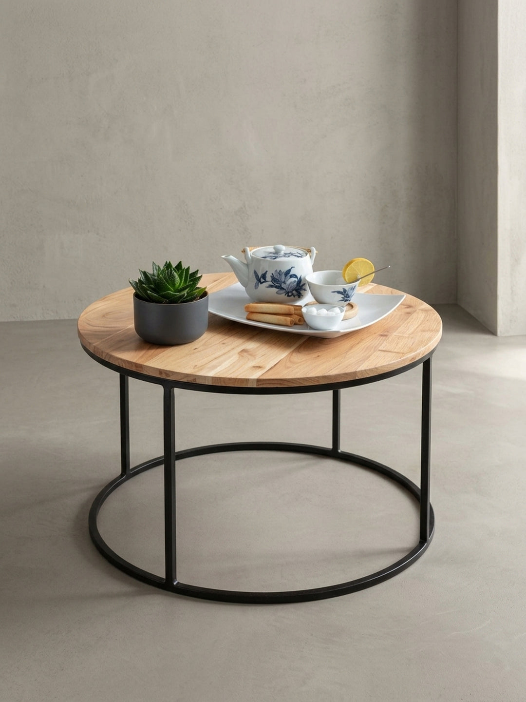 Alternative Perspektive des kleinen Wohnzimmertisches. Der Materialmix aus warmem Massivholz und kühlem Metall unterstreicht den zeitlosen Charakter dieses runden Beistelltisches._