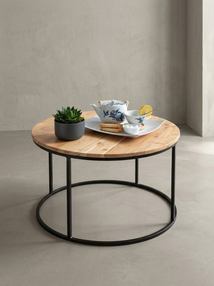 Alternative Perspektive des kleinen Wohnzimmertisches. Der Materialmix aus warmem Massivholz und kühlem Metall unterstreicht den zeitlosen Charakter dieses runden Beistelltisches._