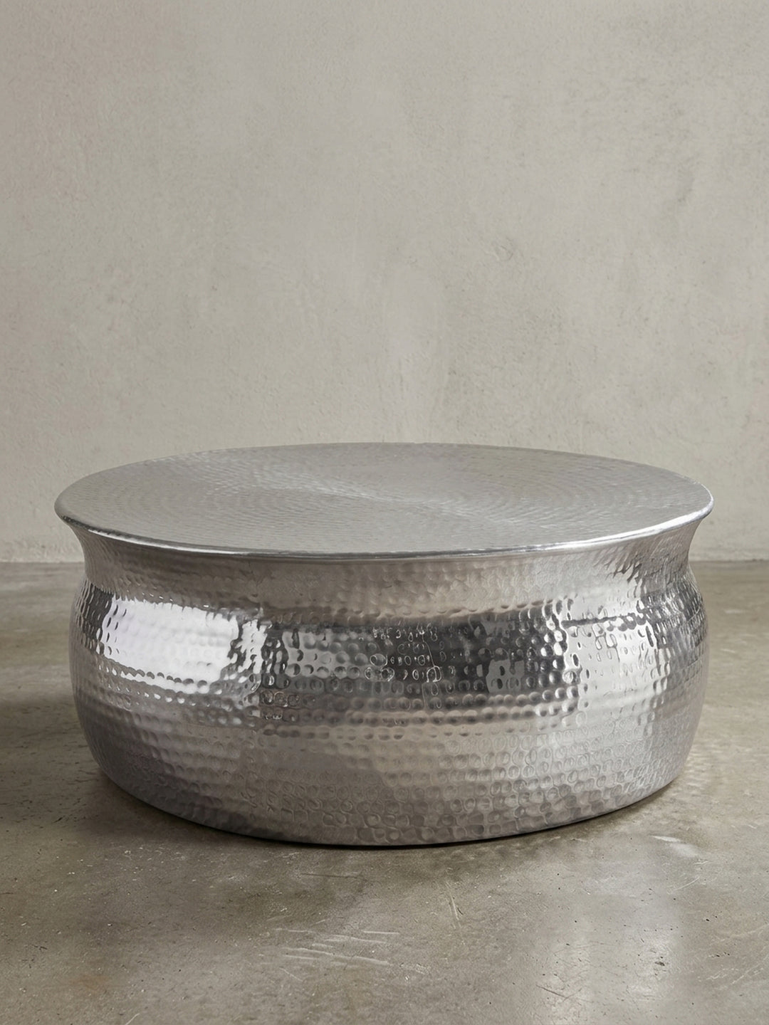 Silberner Couchtisch aus Metall in bauchiger Form freigestellt vor weißem Hintergrund. Der 31cm flache Loungetisch besticht durch sein orientalisches Struktur-Design._