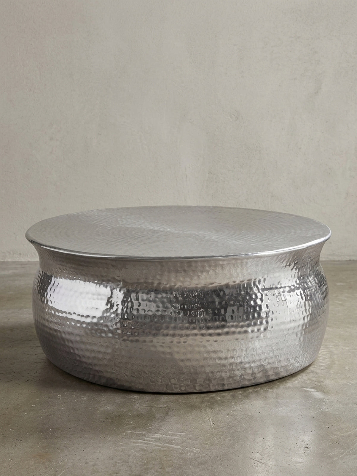 Silberner Couchtisch aus Metall in bauchiger Form freigestellt vor weißem Hintergrund. Der 31cm flache Loungetisch besticht durch sein orientalisches Struktur-Design._