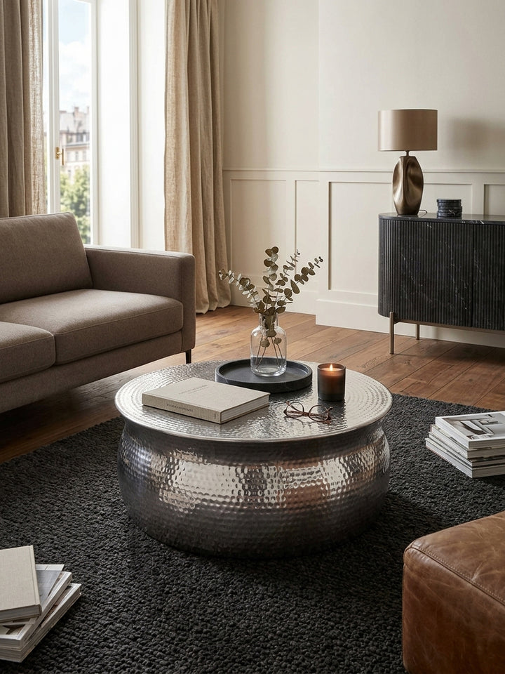 Draufsicht auf den runden silbernen Metalltisch im Wohnzimmer. Der kompakte Sofatisch mit 75cm Durchmesser fügt sich perfekt in die luxuriöse, moderne Lounge-Sitzgruppe ein._