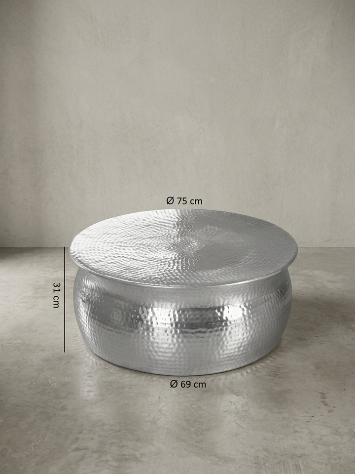 Detailansicht der Rückseite des runden Aluminiumtisches. Die durchgehende Hammerschlag-Struktur ohne sichtbare Nähte unterstreicht die hochwertige Verarbeitung des Metalls._