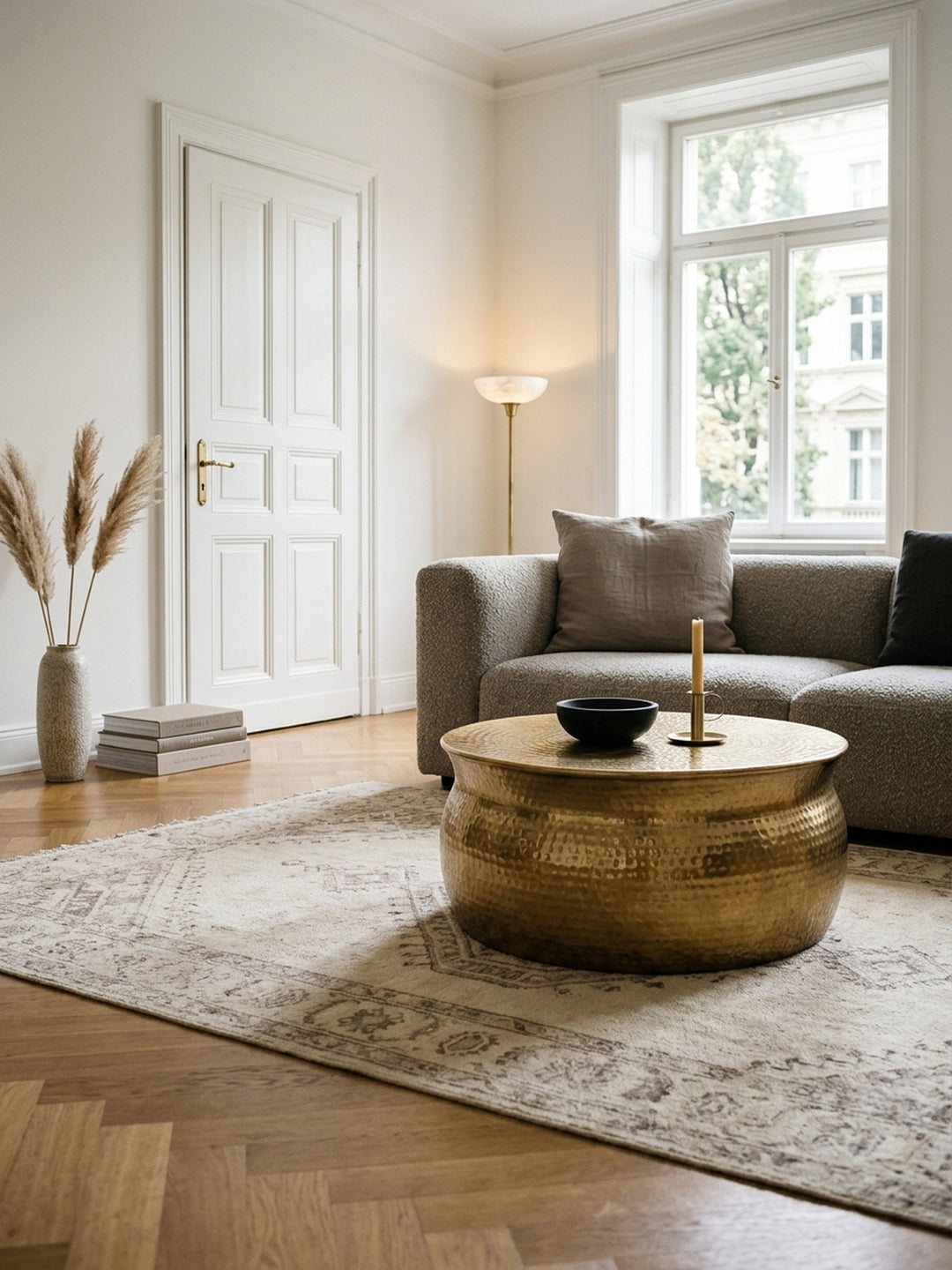 Ein luxuriöses Wohnzimmer mit einem runden Couchtisch aus goldenem Aluminium im Zentrum. Das elegante Hammerschlag-Design des 75x31 cm Tisches reflektiert sanft das Licht._