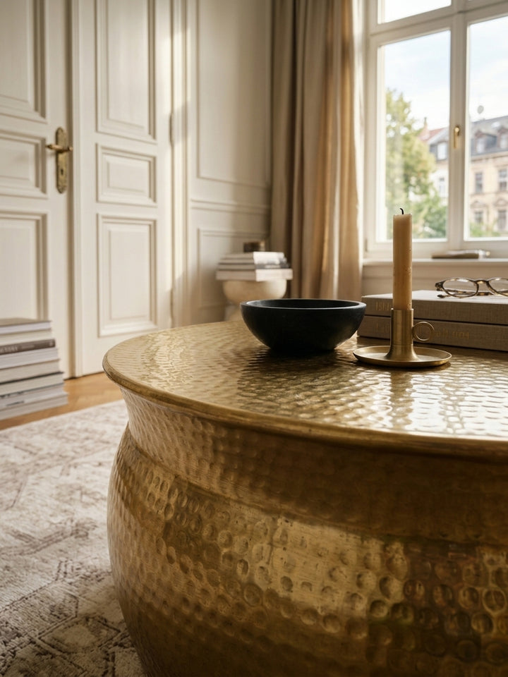 Nahaufnahme der strukturierten Oberfläche eines goldenen Aluminium-Couchtisches. Das orientalische Hammerschlag-Design verleiht dem runden Beistelltisch eine besondere Haptik._