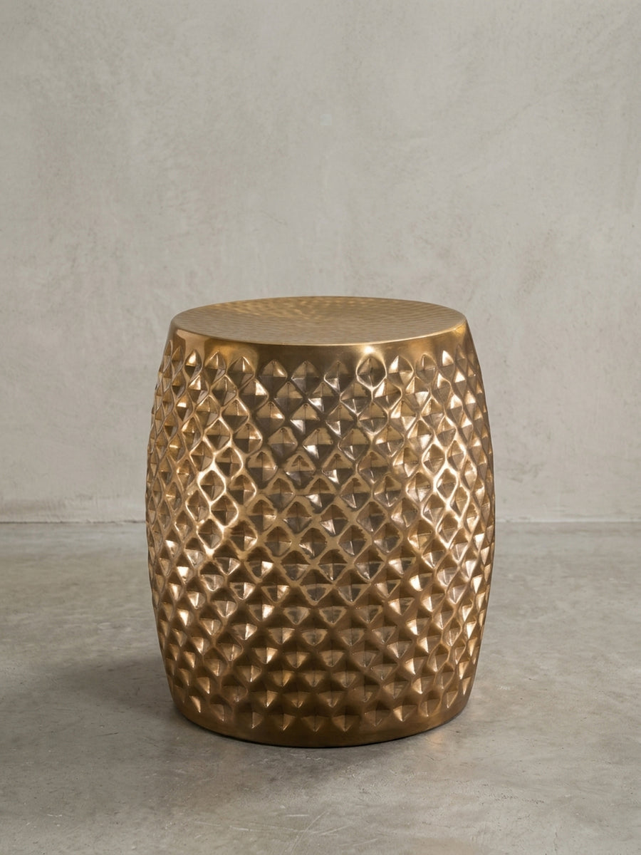 Vorderansicht des kompakten Beistelltisches in Gold auf weißem Hintergrund. Die fassförmige Silhouette aus 100% Aluminium besticht durch das umlaufende, orientalische Muster._
