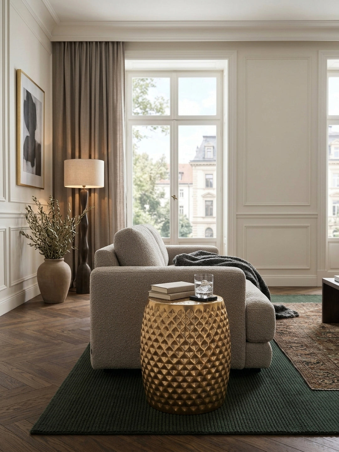 Eleganter runder Beistelltisch aus gold lackiertem Aluminium im luxuriösen Wohnzimmer. Der orientalische fassförmige Couchtisch mit Hammerschlag-Design steht neben einem dunklen Sofa._