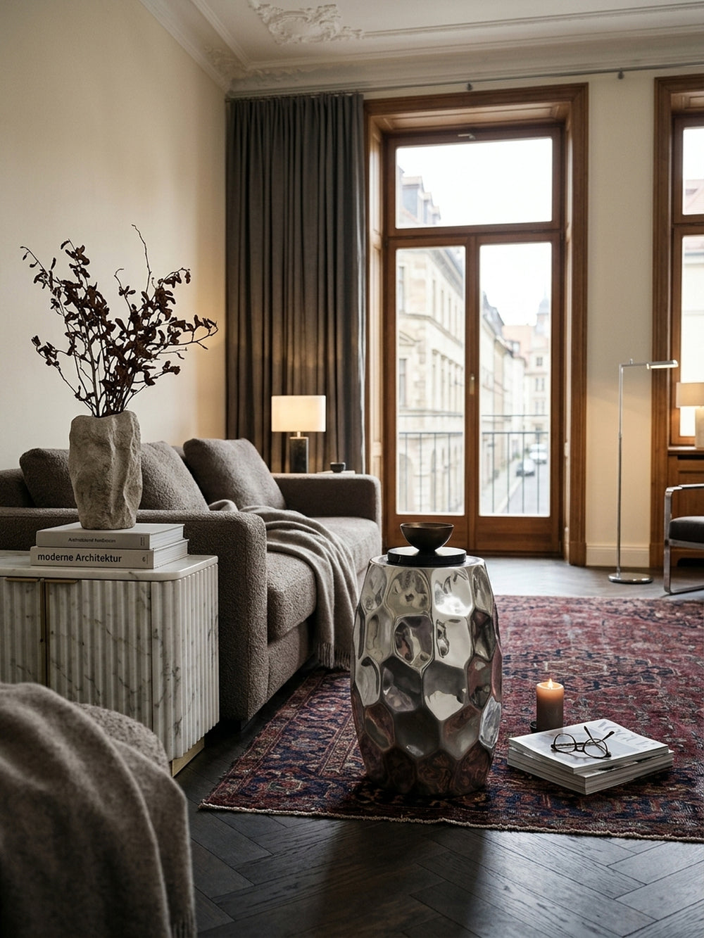 Silberner Beistelltisch aus Aluminium im orientalischen Hammerschlag-Design, stilvoll arrangiert im modernen Wohnzimmer neben einem Lounge-Sessel. Maß L:30xB:30xH:47cm._