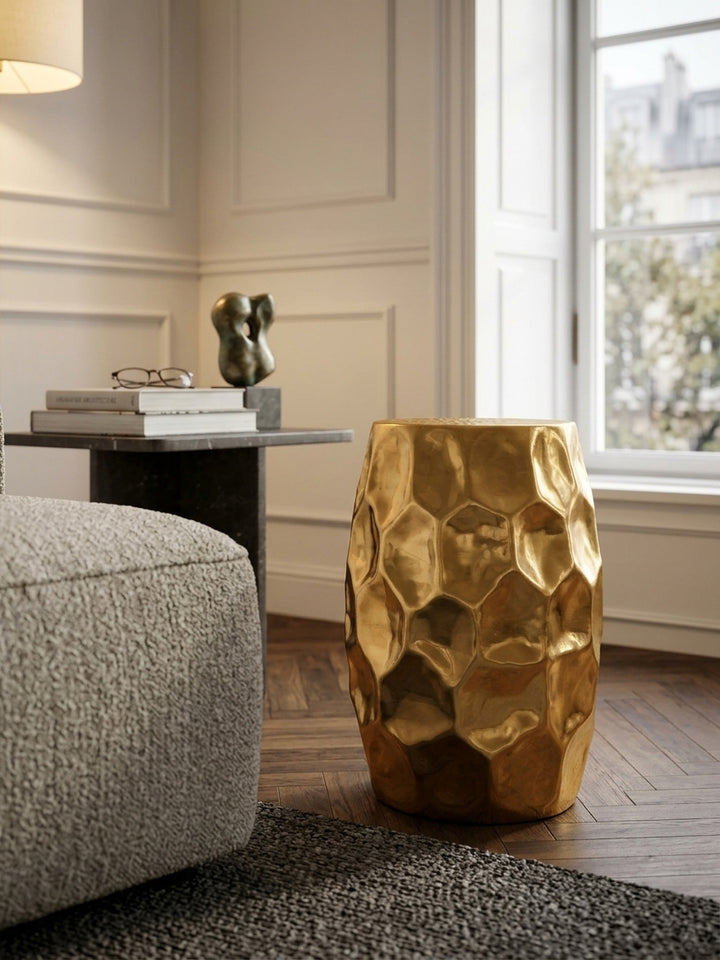 Makroaufnahme der goldenen Hammerschlag Oberfläche des Beistelltisches. Das orientalische Wabenmuster im Aluminium reflektiert warmes Licht im gehobenen Wohnzimmer Ambiente._