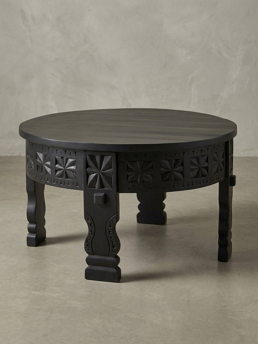 Runder Salontisch aus schwarzem Massivholz in der 3/4-Ansicht, die die Tiefe der geschnitzten Ornamente und die solide Konstruktion des Wohnzimmertisches betont._