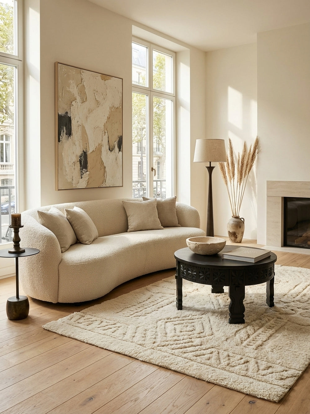 Schwarzer runder Mango Holz Couchtisch mit Schnitzereien im Zentrum eines hellen Wohnzimmers auf einem beigen Teppich, dekoriert mit einer goldenen Elefantenfigur._