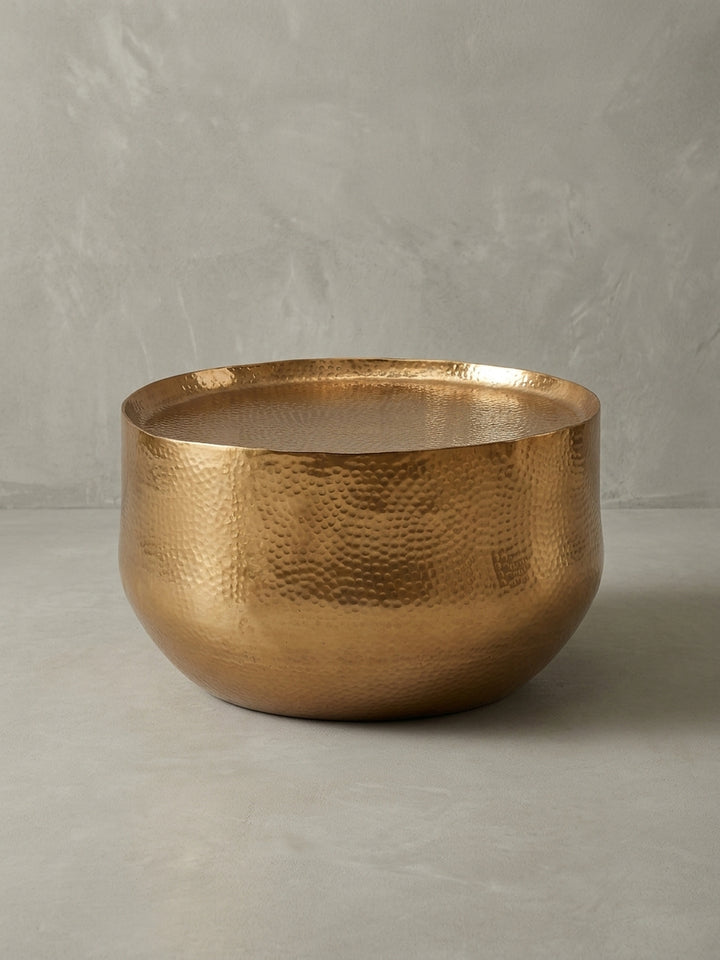 Dreiviertelansicht des goldenen Couchtischs aus Aluminium, der die runde Form und die von Hand gehämmerte Textur der Oberfläche betont._