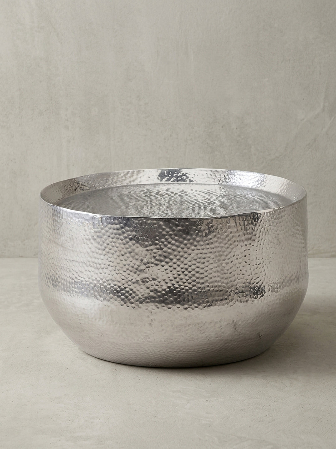 Der runde Wohnzimmertisch aus silberfarben lackiertem Aluminium in der Gesamtansicht, ein Schmuckstück im Hammerschlag-Design für jedes Interieur._