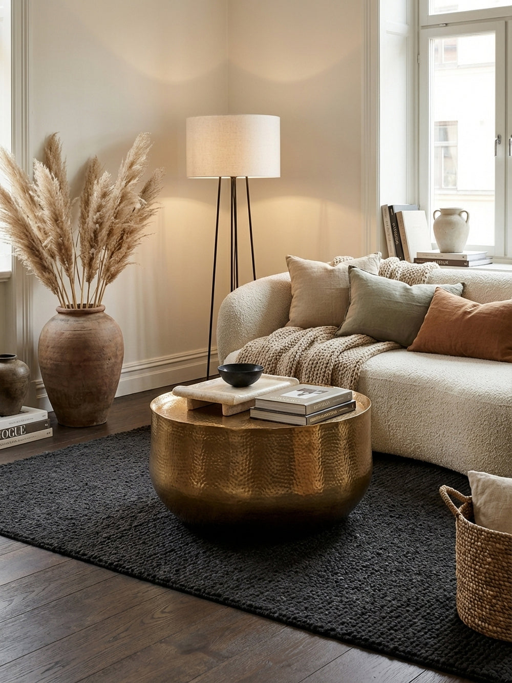 Eleganter runder Couchtisch in Gold, zentral platziert in einem modernen Wohnzimmer auf einem dunklen Teppich vor einem Sofa, mit dezenter Dekoration._