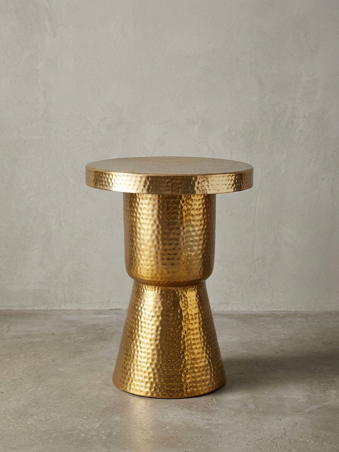 Frontale Ansicht des goldenen Beistelltischs auf weißem Hintergrund. Die skulpturale, taillierte Form des 59 cm hohen Aluminiumtisches im orientalischen Stil wirkt modern und edel._