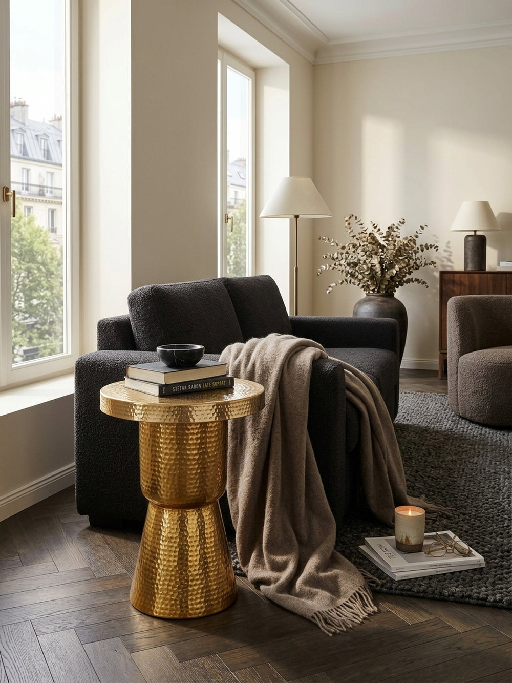 Draufsicht auf den runden Beistelltisch in Gold im Wohnbereich. Die 43 cm breite Ablagefläche aus gehämmertem Aluminium bietet Platz für Bücher, umgeben von modernem Interieur._