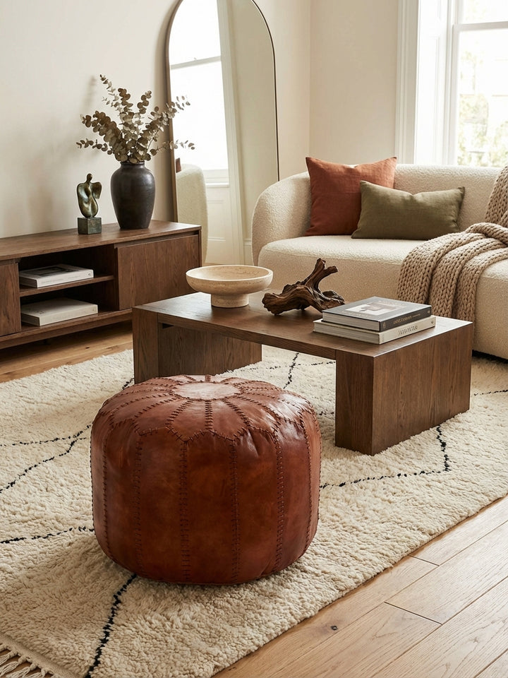 Runder Leder Pouf in Braun von oben gesehen, platziert auf einem texturierten Teppich als stilvolles Accessoire im Wohnbereich._